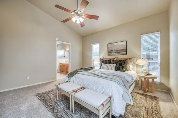a spacious bedroom with a bed a chandelier and a dresser