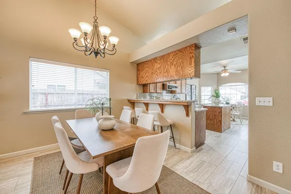 a dining room with wooden floor a chandelier a glass table and chairs