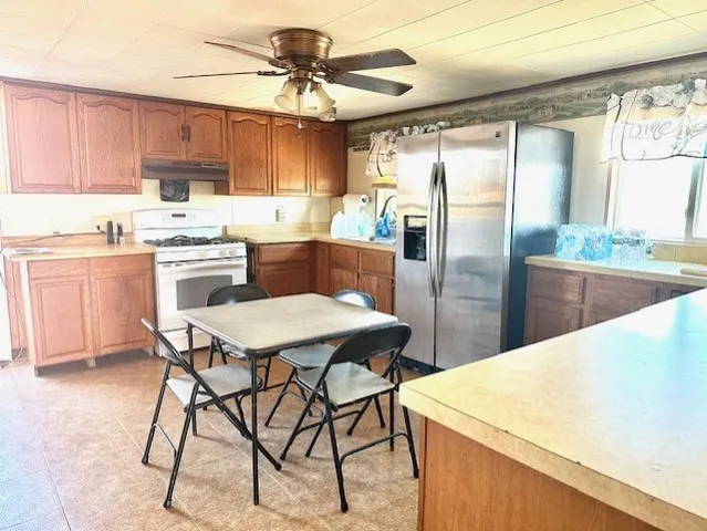 a kitchen with stainless steel appliances kitchen island granite countertop a table chairs refrigerator and sink