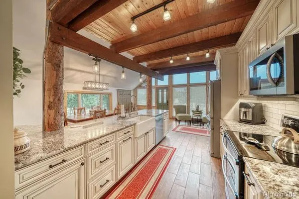 a large white kitchen with stainless steel appliances granite countertop a stove and a large window with wooden floors