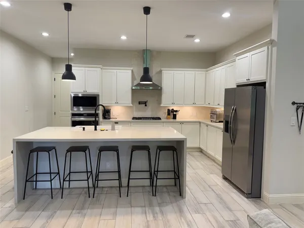 a kitchen with stainless steel appliances a table chairs refrigerator and microwave