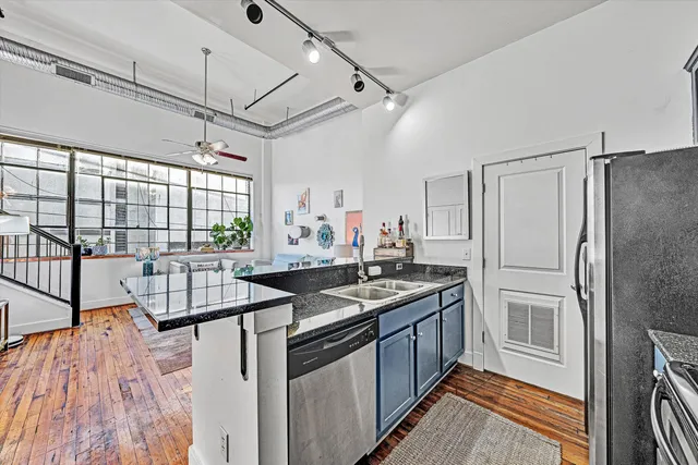 a kitchen with stainless steel appliances granite countertop a stove a sink dishwasher a refrigerator and cabinets with wooden floor