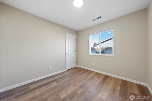 a view of empty room with wooden floor and window