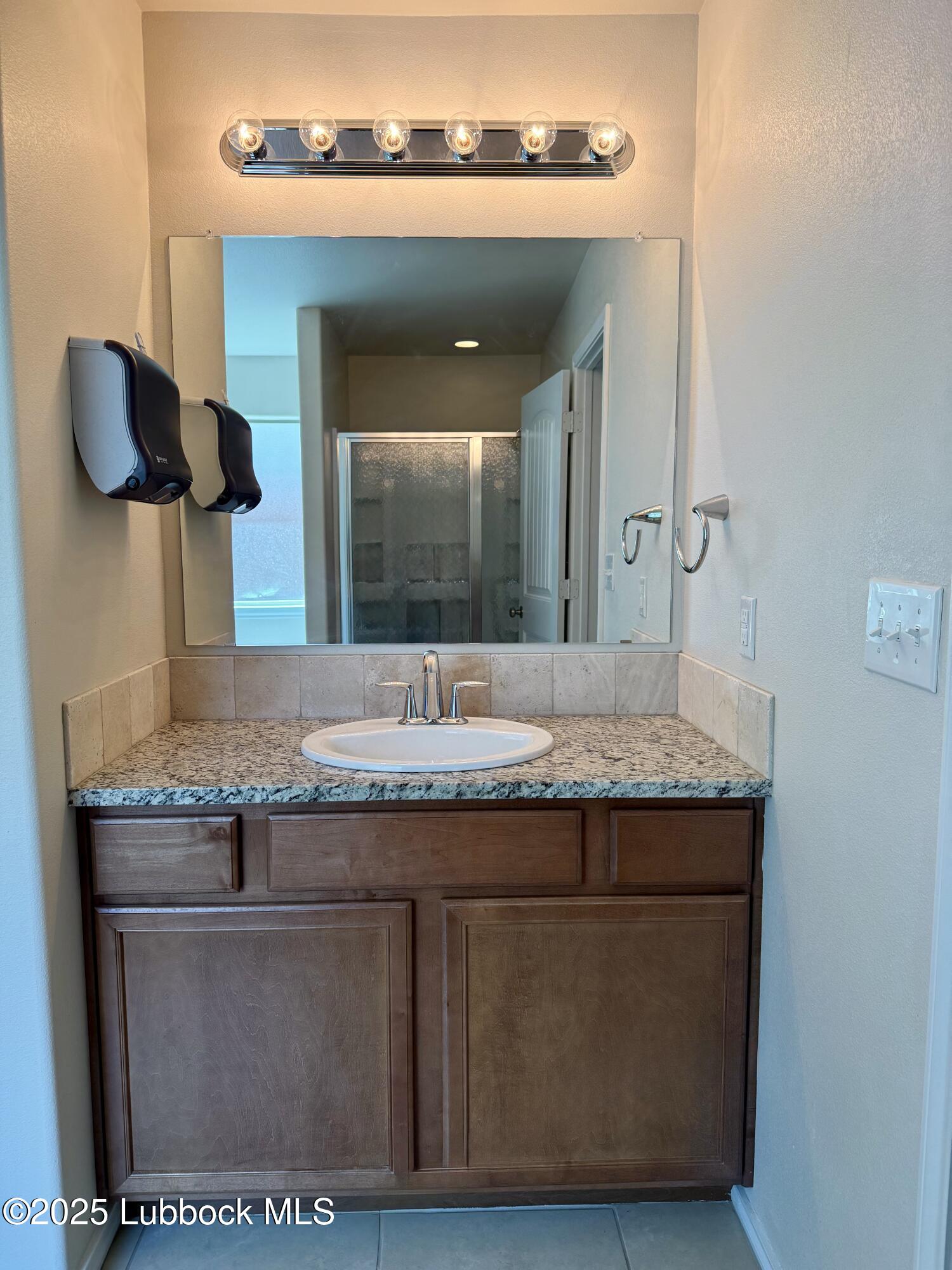 7046 95th Street Lubbock, TX 79424 - Photo 14 of 23 a bathroom with a granite countertop sink and a mirror