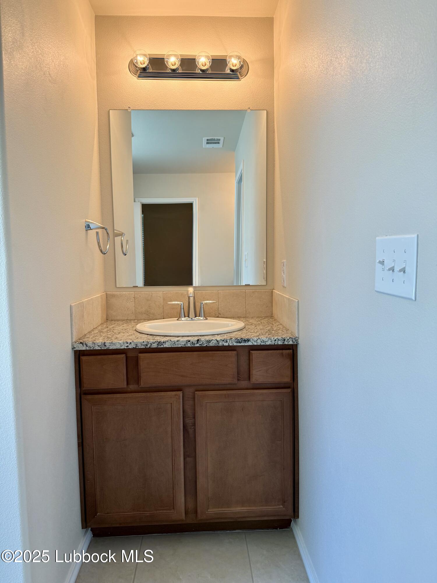 7046 95th Street Lubbock, TX 79424 - Photo 15 of 23 a bathroom with a sink and a mirror