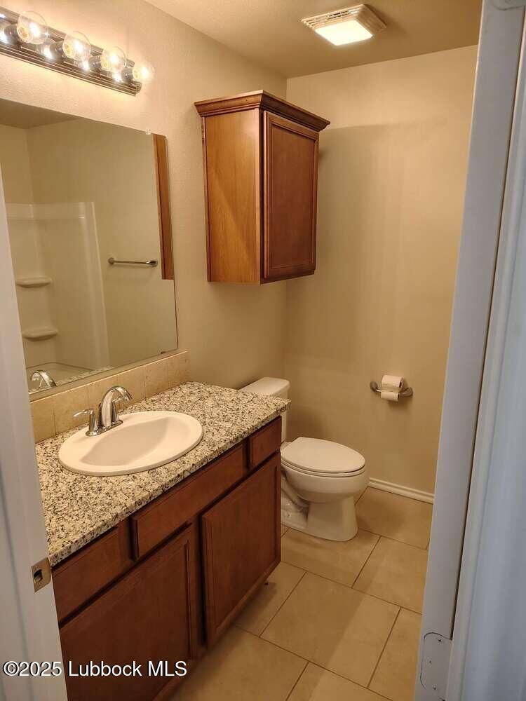7046 95th Street Lubbock, TX 79424 - Photo 18 of 23 a bathroom with a granite countertop sink a toilet and a mirror