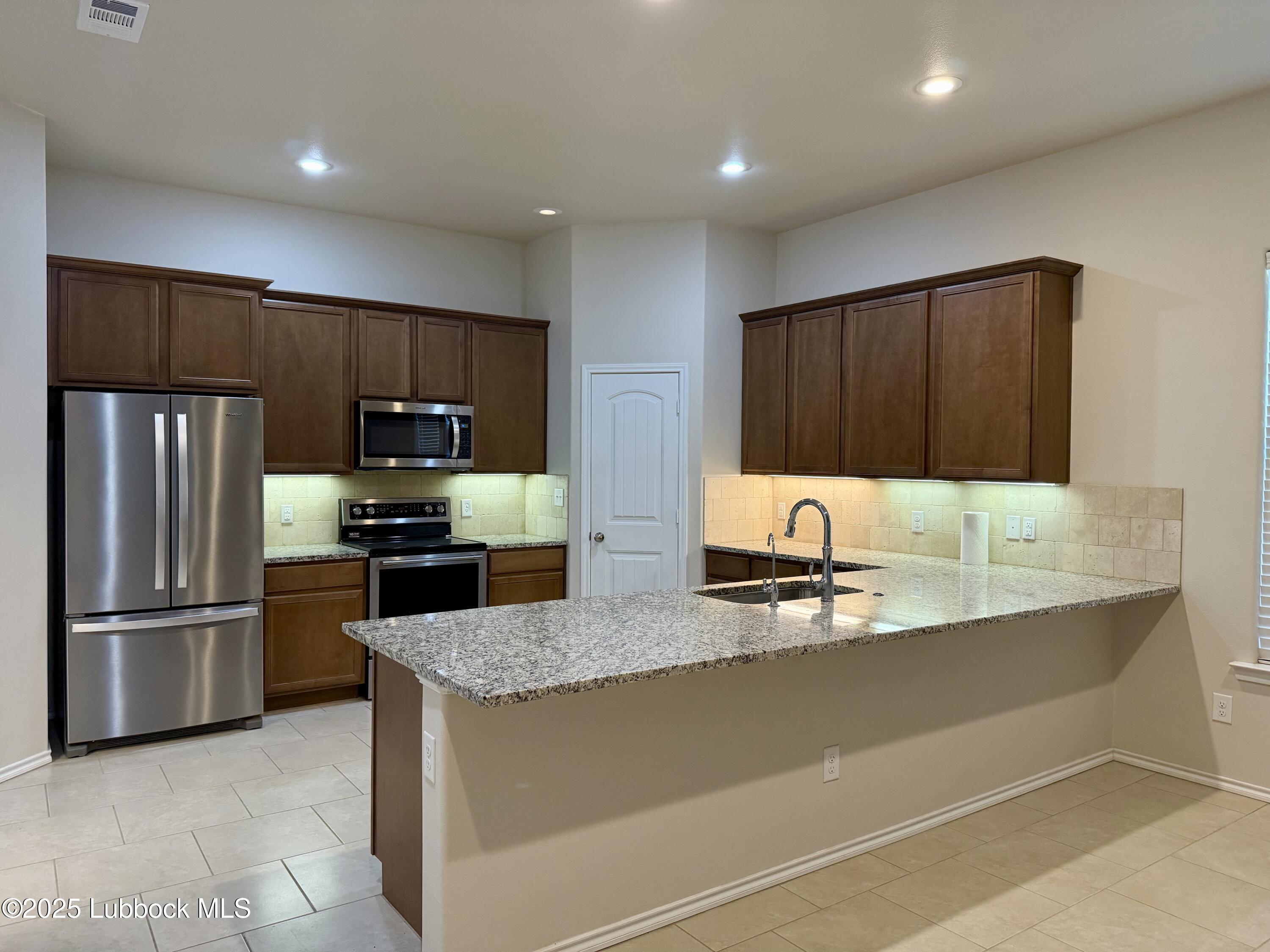 7046 95th Street Lubbock, TX 79424 - Photo 2 of 23 a kitchen with stainless steel appliances granite countertop a refrigerator and a sink