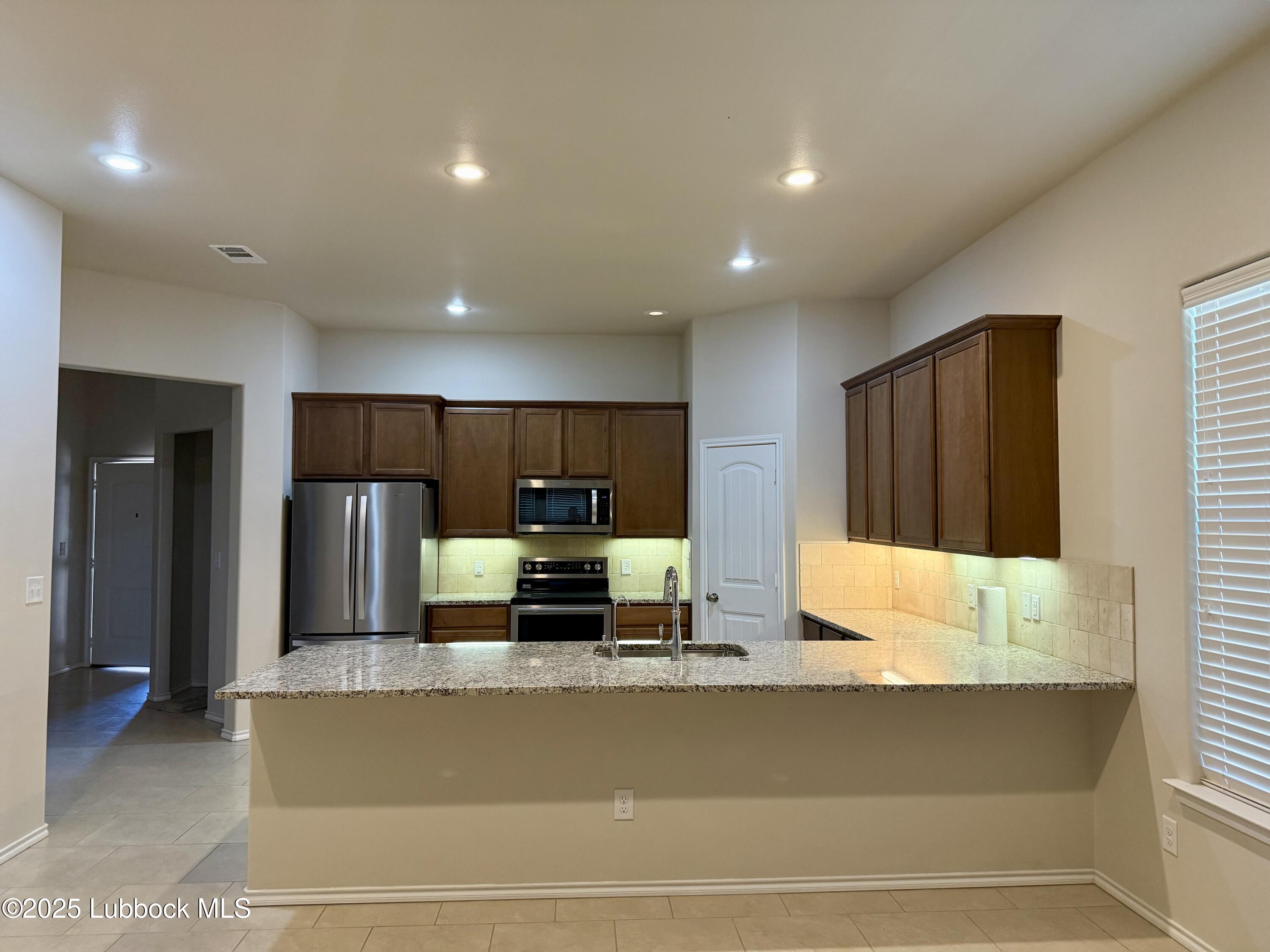 7046 95th Street Lubbock, TX 79424 - Photo 3 of 23 a view of kitchen with stainless steel appliances kitchen island sink refrigerator and microwave