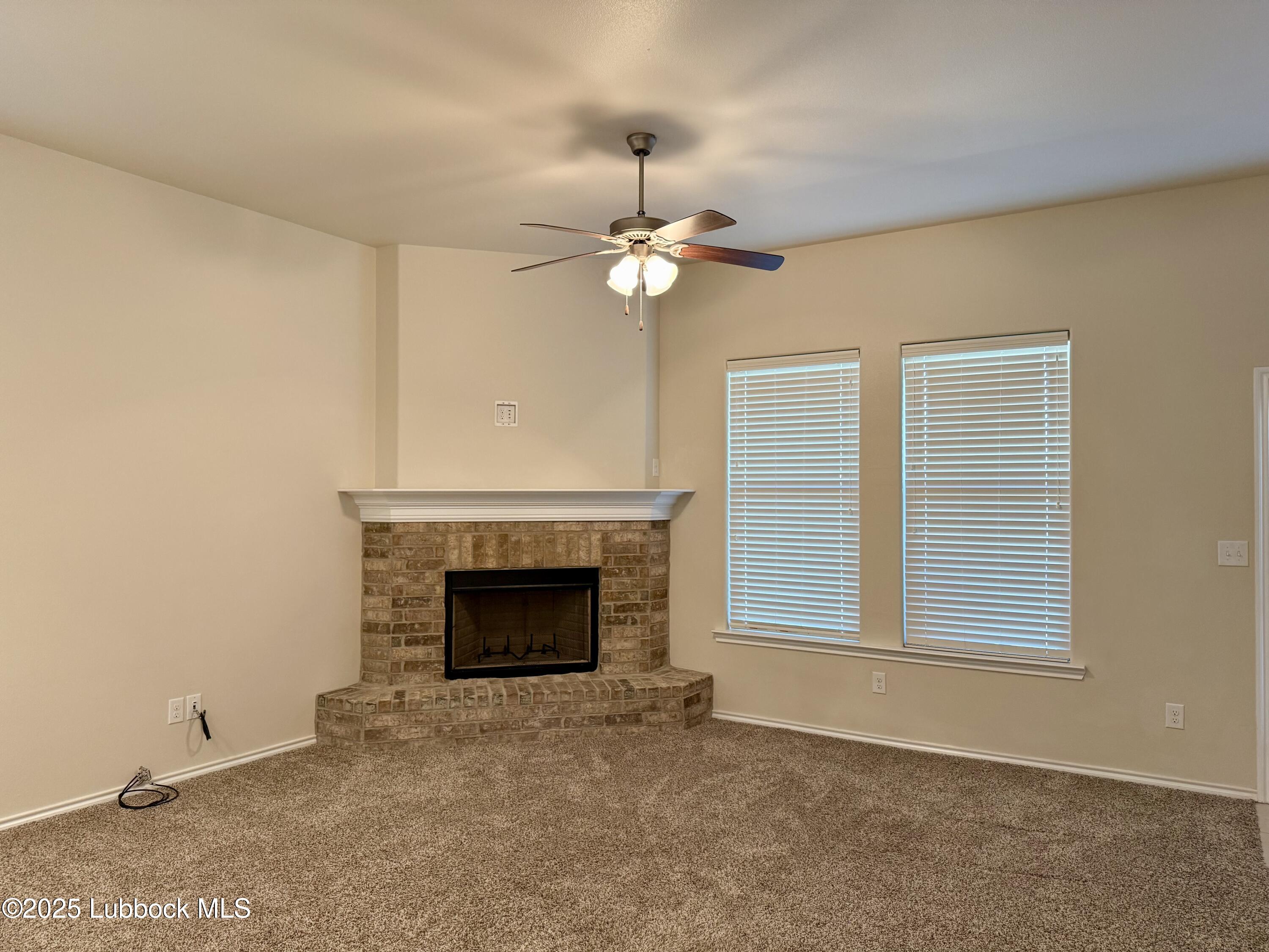 7046 95th Street Lubbock, TX 79424 - Photo 4 of 23 an empty room with fireplace and fan