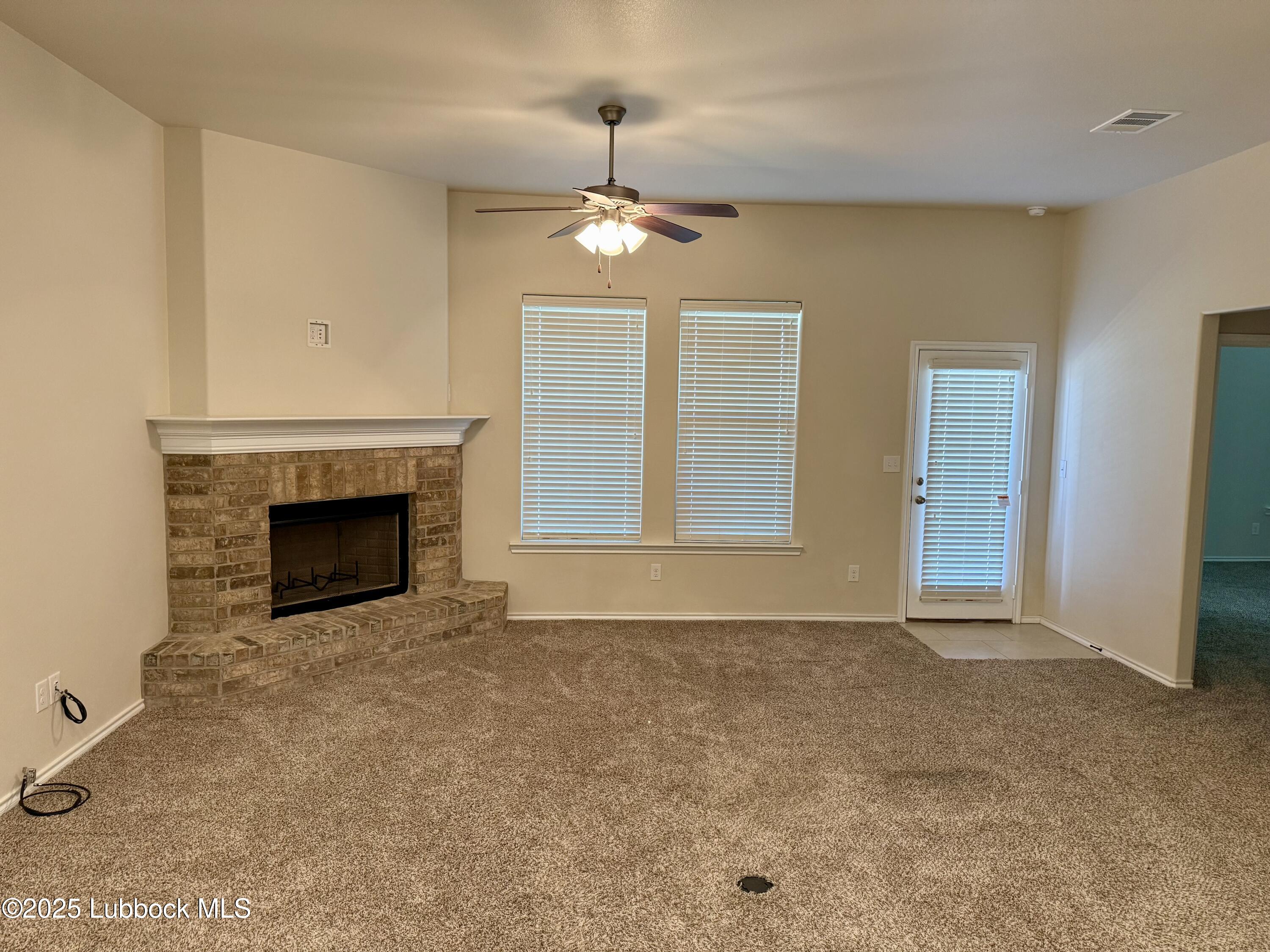 7046 95th Street Lubbock, TX 79424 - Photo 5 of 23 an empty room with windows fireplace and a kitchen view