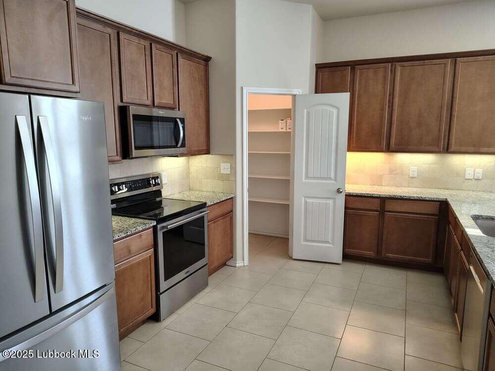 7046 95th Street Lubbock, TX 79424 - Photo 8 of 23 a kitchen with granite countertop a refrigerator and a stove
