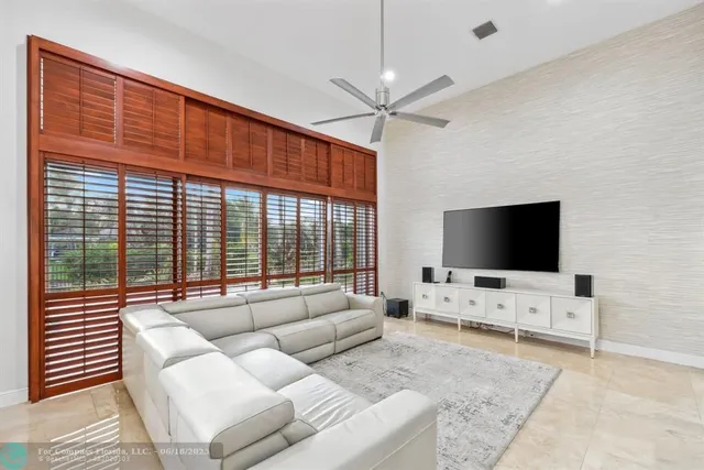 a view of an empty room with wooden floor and a ceiling fan