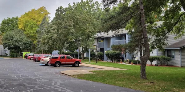 a car parked in front of white house with a small yard and a large tree