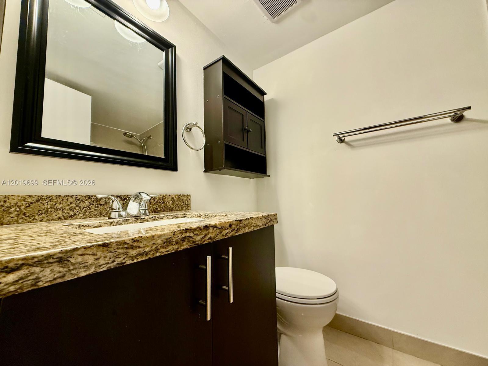 3470 Foxcroft Road, Unit 204 Miramar, FL 33025 - Photo 17 of 40 a bathroom with a granite countertop sink toilet and mirror