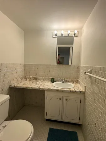 a bathroom with a granite countertop toilet sink and mirror