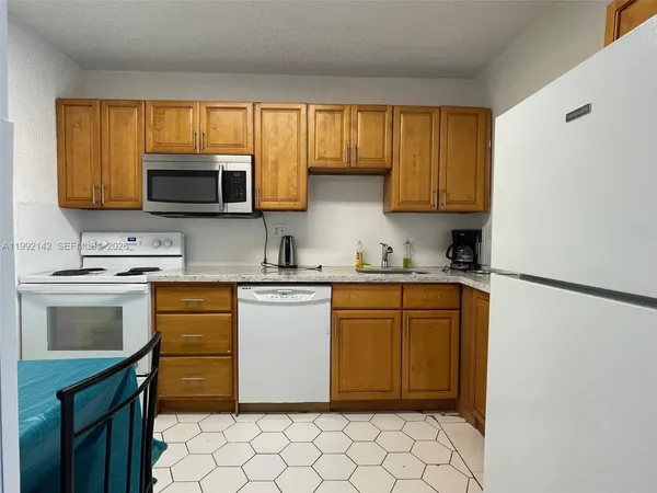 a kitchen with granite countertop a refrigerator stove top oven a sink and dishwasher