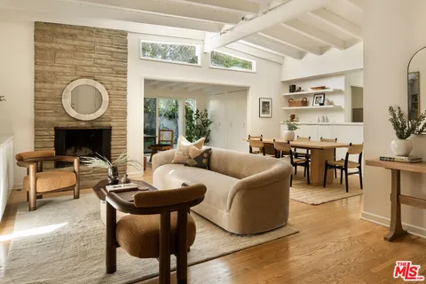 a living room with furniture a fireplace a dining table and a large window