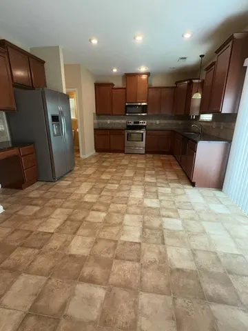 a large kitchen with stainless steel appliances granite countertop a refrigerator and a sink