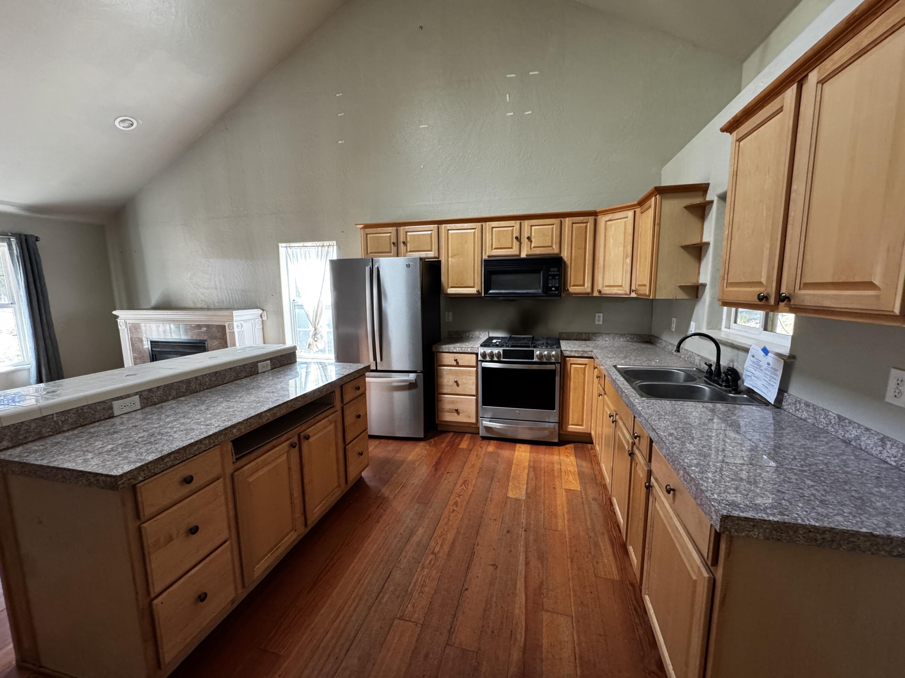 240 Bluff Street Butte Falls, OR 97522 - Photo 9 of 34 a large kitchen with wooden floors and stainless steel appliances