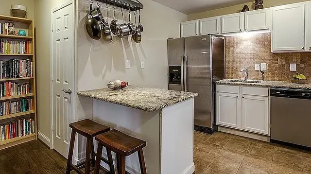 a kitchen with stainless steel appliances granite countertop a refrigerator a stove and a wooden floors