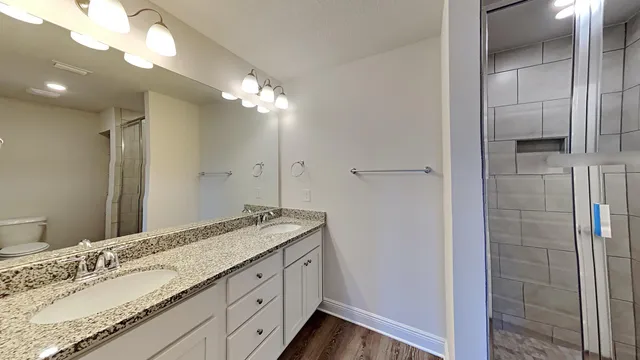 a spacious bathroom with a granite countertop sink a mirror and shower