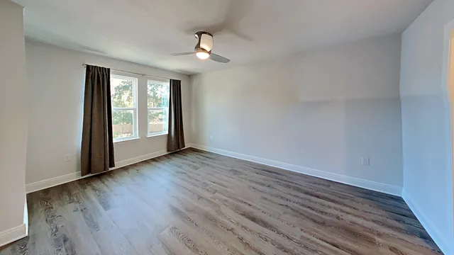 a view of an empty room with wooden floor and a window