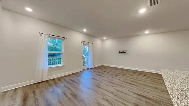 an empty room with wooden floor and windows