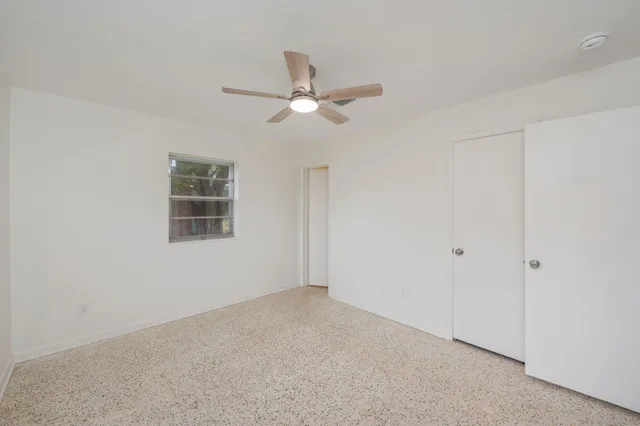 an empty room with windows and fan