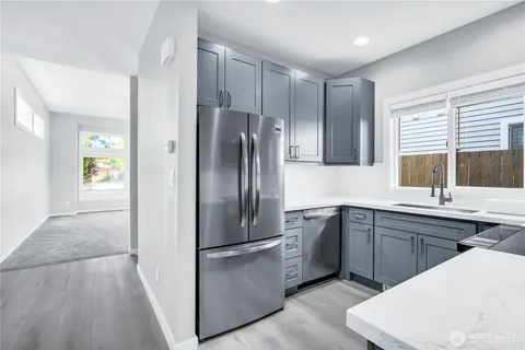 a kitchen with stainless steel appliances a sink a refrigerator and wooden floor