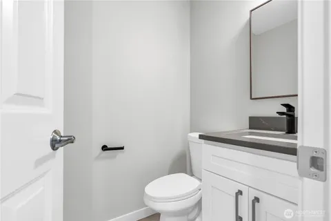 a bathroom with a granite countertop toilet sink and mirror