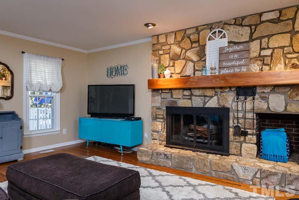 6932 Three Bridges Circle Raleigh, NC 27613 - Photo 3 of 25 a living room with furniture a flat screen tv and a fireplace