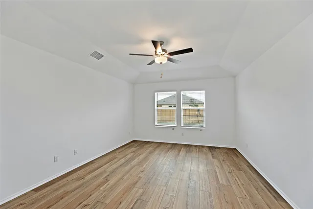 an empty room with wooden floor and windows