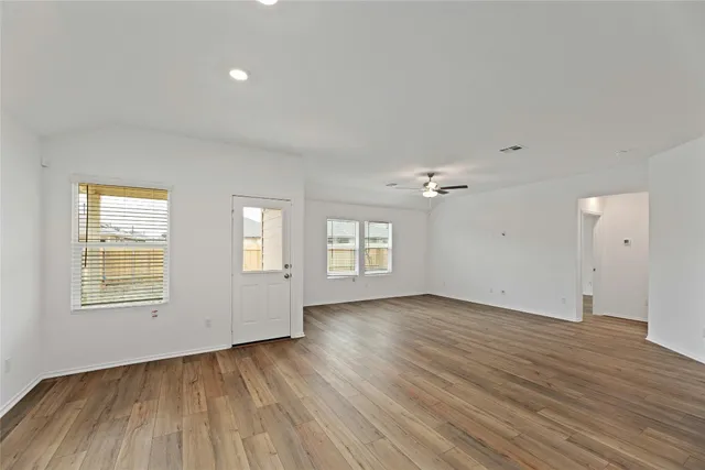 a view of an empty room with a window and wooden floor