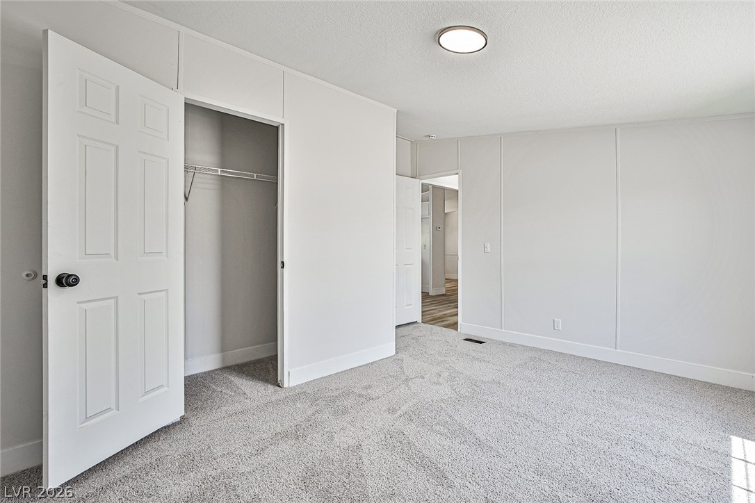 273 Aztec Lane Henderson, NV 89015 - Photo 23 of 28 A spacious bedroom features plush carpeting and a convenient closet, creating a serene personal retreat.
