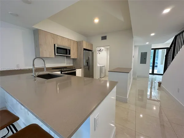 a living room with stainless steel appliances furniture a refrigerator and a sink