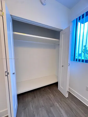 a view of closet area with window and wooden floor