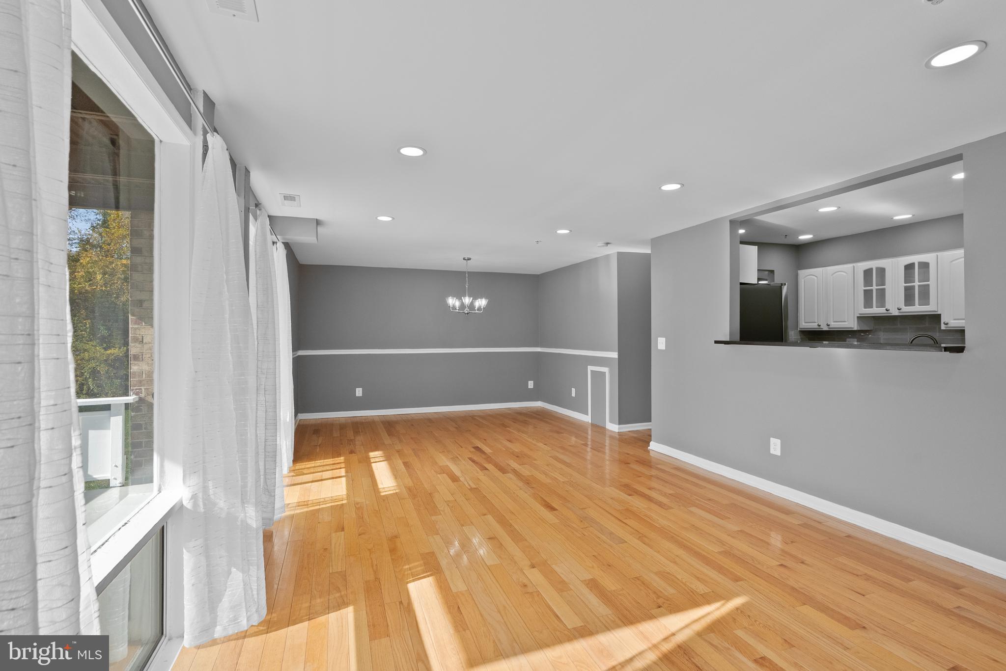542 Wilson Bridge Drive, Unit 6743 B2 Oxon Hill, MD 20745 - Photo 6 of 27 a view of an empty room with wooden floor and a kitchen