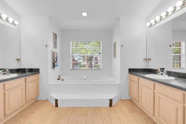 a bathroom with a granite countertop sink a large mirror and a bathtub