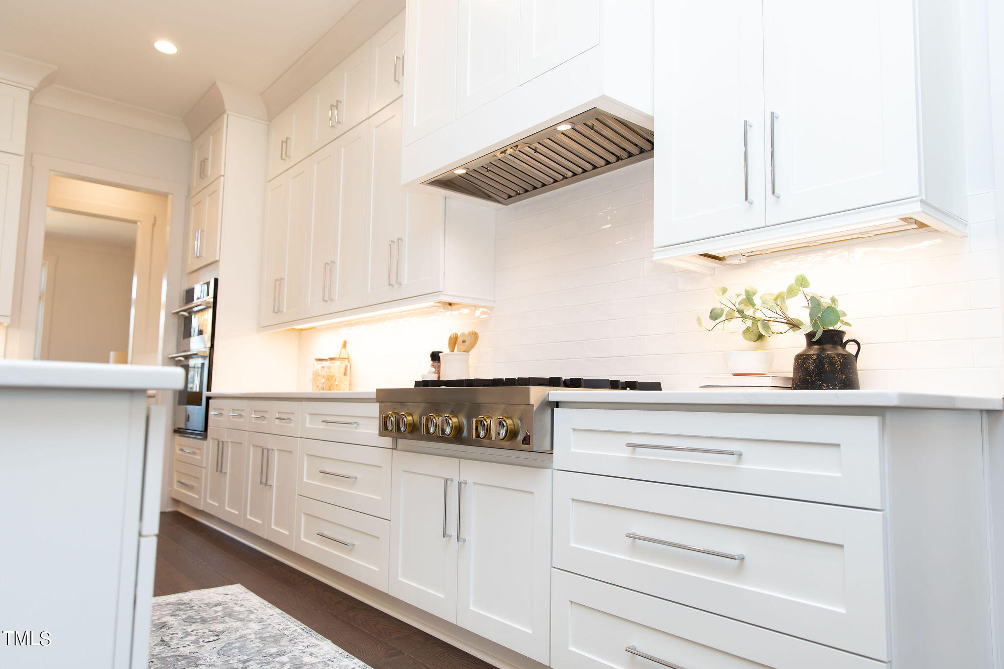 9412 Rawson Avenue Raleigh, NC 27613 - Photo 9 of 53 a kitchen with white cabinets and chandelier