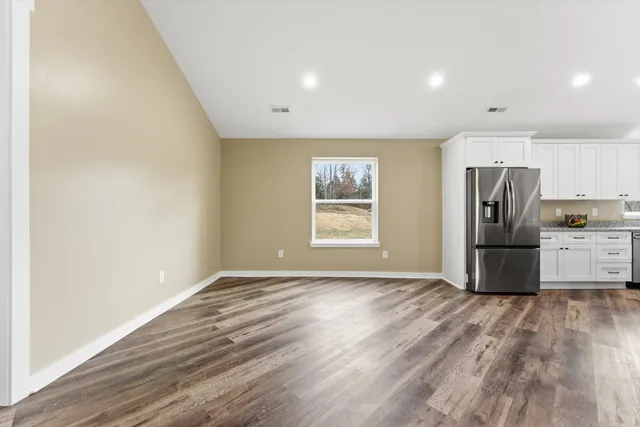 a view of kitchen with stainless steel appliances wooden floor and large window