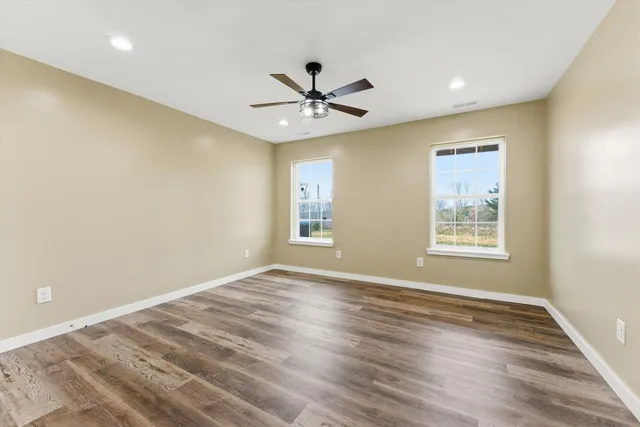 a view of an empty room with window and wooden floor