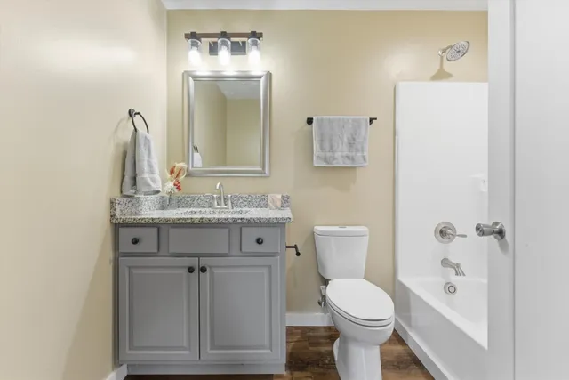 a bathroom with a granite countertop toilet sink and mirror