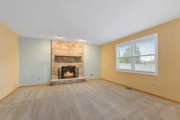 a view of an empty room with a window and a fireplace