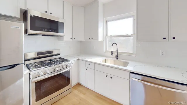 a kitchen with white cabinets stainless steel appliances and sink