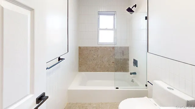 a bathroom with a bathtub a window and a shower