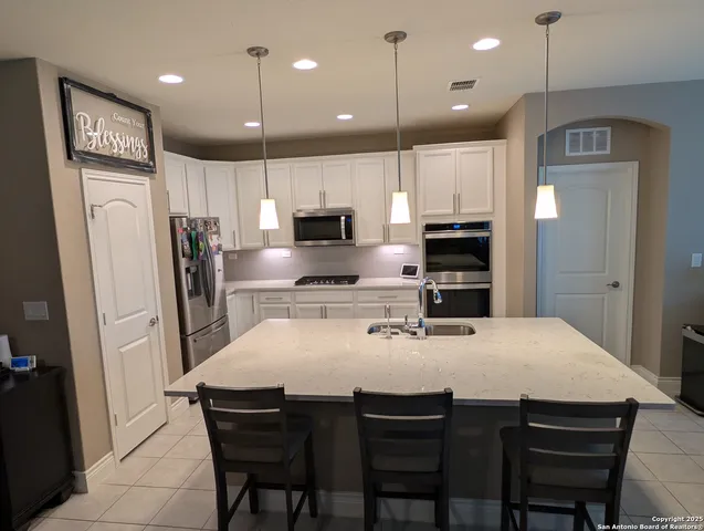 a kitchen with stainless steel appliances granite countertop a sink refrigerator and cabinets