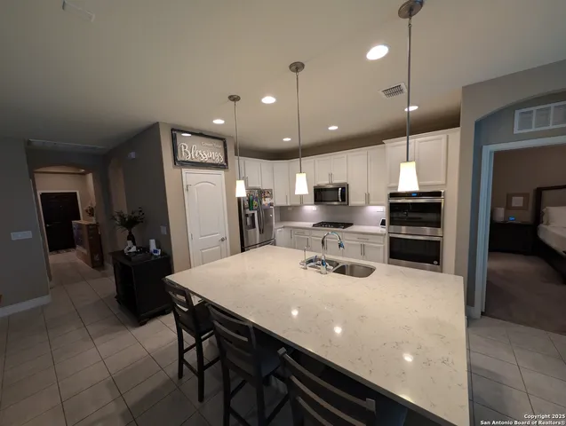 a kitchen with sink a refrigerator and chairs