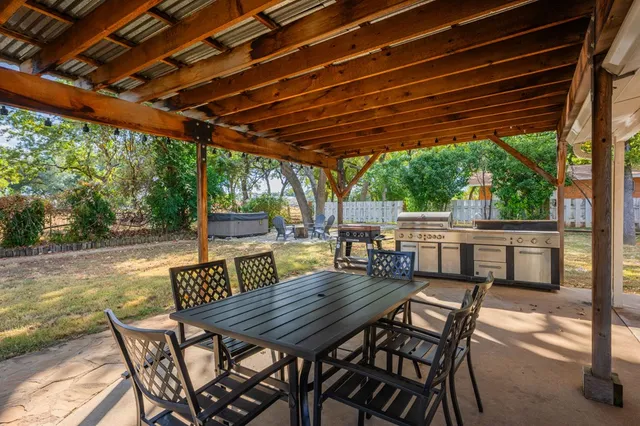 a view of yard with table and chairs under an umbrella with a barbeque