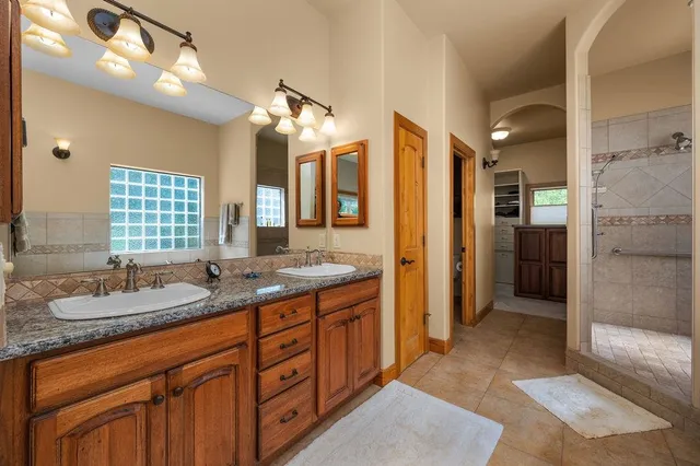 a spacious bathroom with a granite countertop sink mirror and a shower