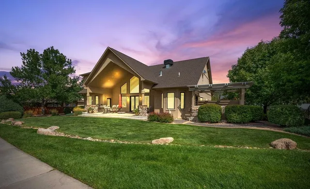 a view of a big house with a big yard and potted plants and large trees